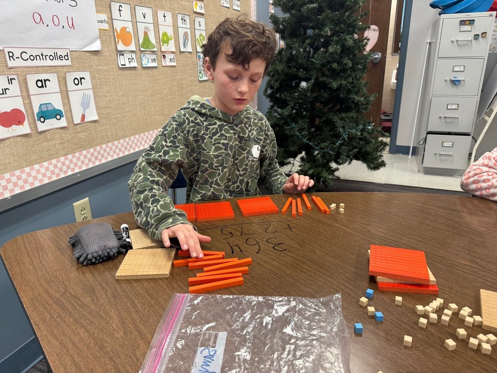 male student using math manipulatives wearing a camo shirt in a classroom with a christmas tree in the background