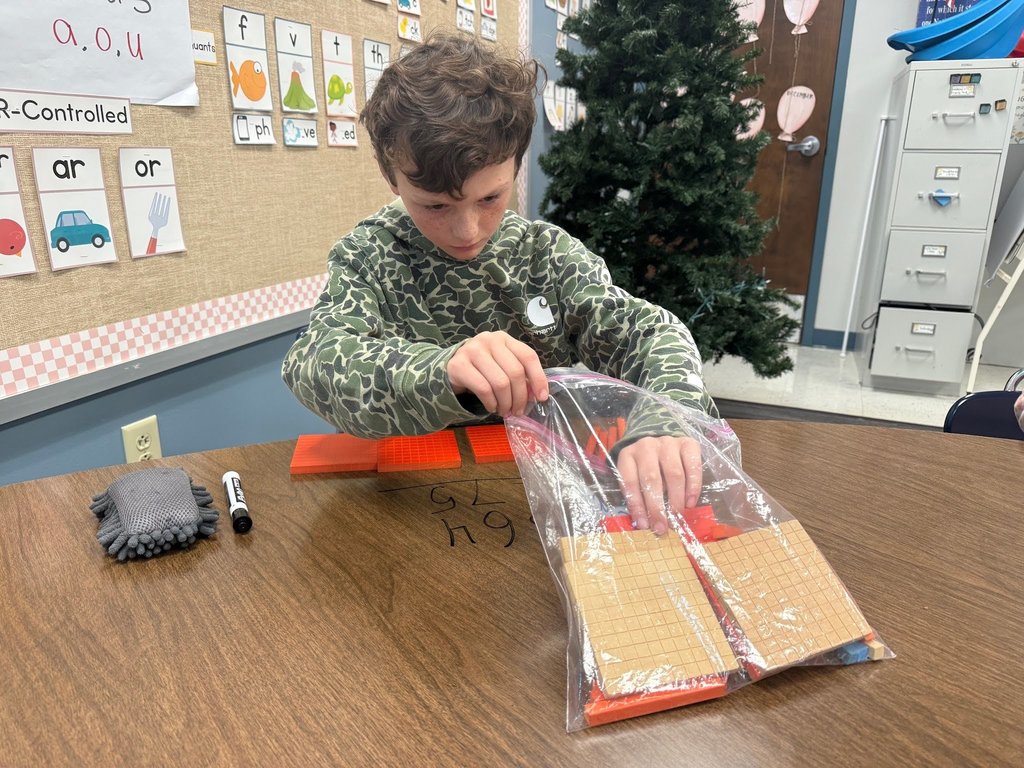 male student using math manipulatives wearing a camo shirt in a classroom with a christmas tree in the background