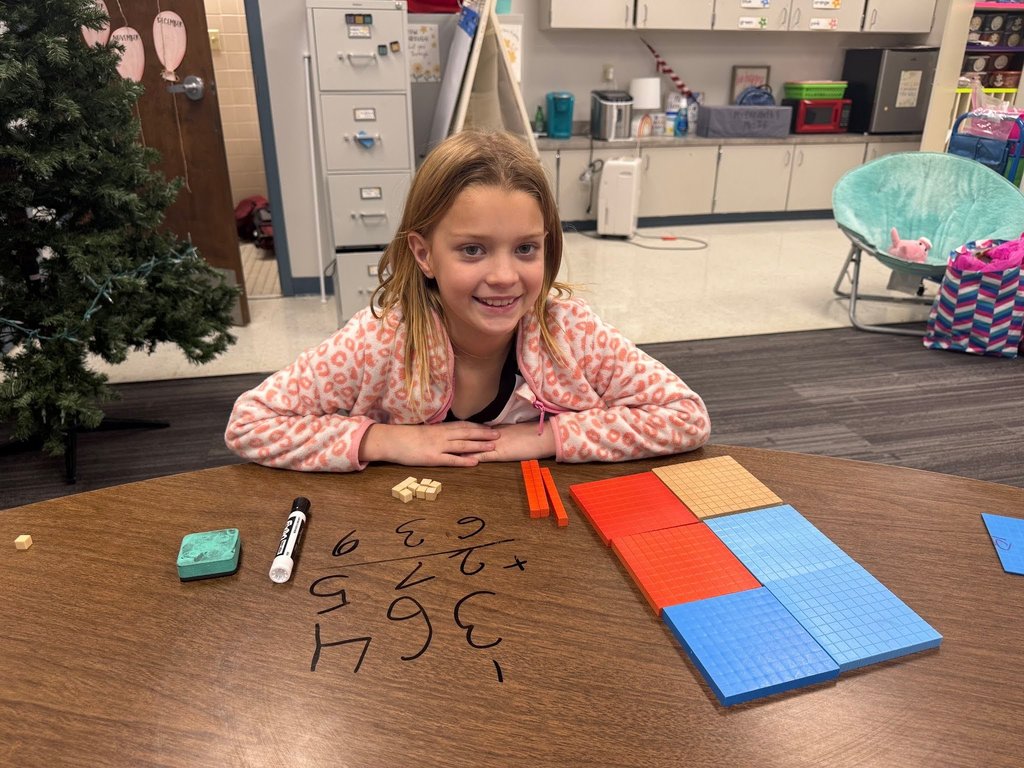 female student using math manipulatives wearing a pink and white shirt in a classroom with a christmas tree in the background