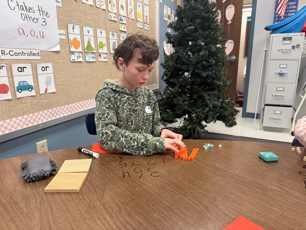 male student using math manipulatives wearing a camo shirt in a classroom with a christmas tree in the background