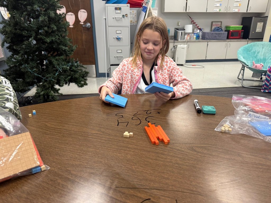female student using math manipulatives wearing a pink and white shirt in a classroom with a christmas tree in the background