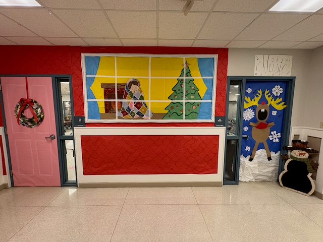 Christmas decoration looks like a child sitting by a fire, wrapped up in a quit looking at a Christmas tree, and another door with a reindeer singing