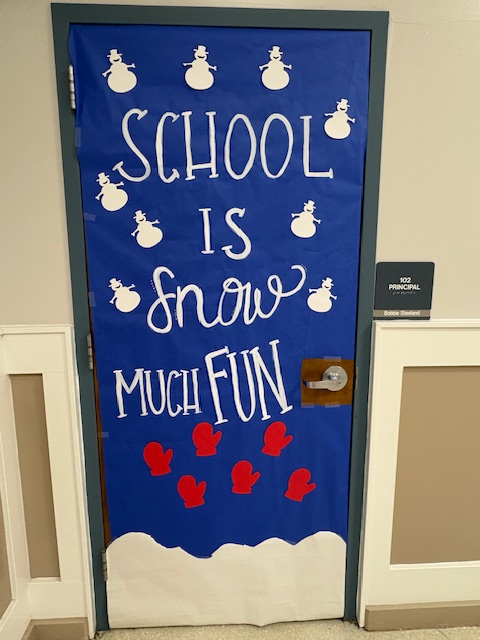 a classdooe decorated with a dark blue background, snow at the bottom, red mittens and white snowmen with the saying School is Snow Much Fun