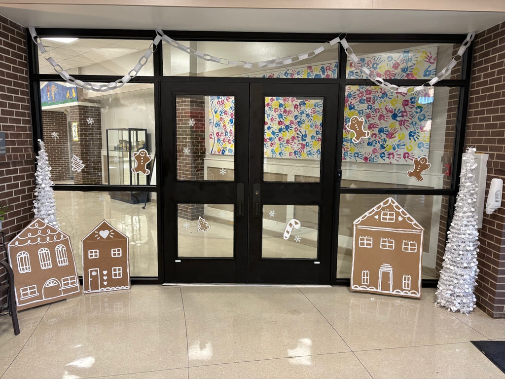 The front foyer of des with white paper chain garland and gingerbread houses and white christmas trees