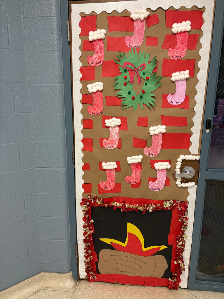 a classroom door decorated like a fireplace with a large mangle with all of the students names on stockings