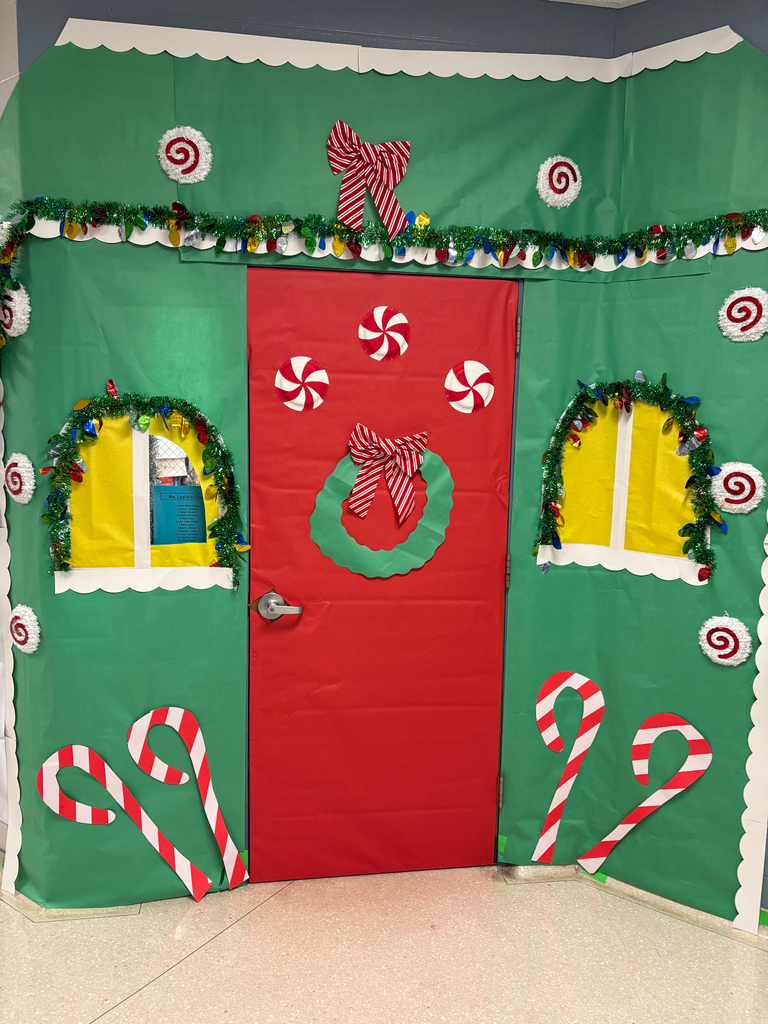 A classroom dorr decorated like a green house with a red door and candy canes all around