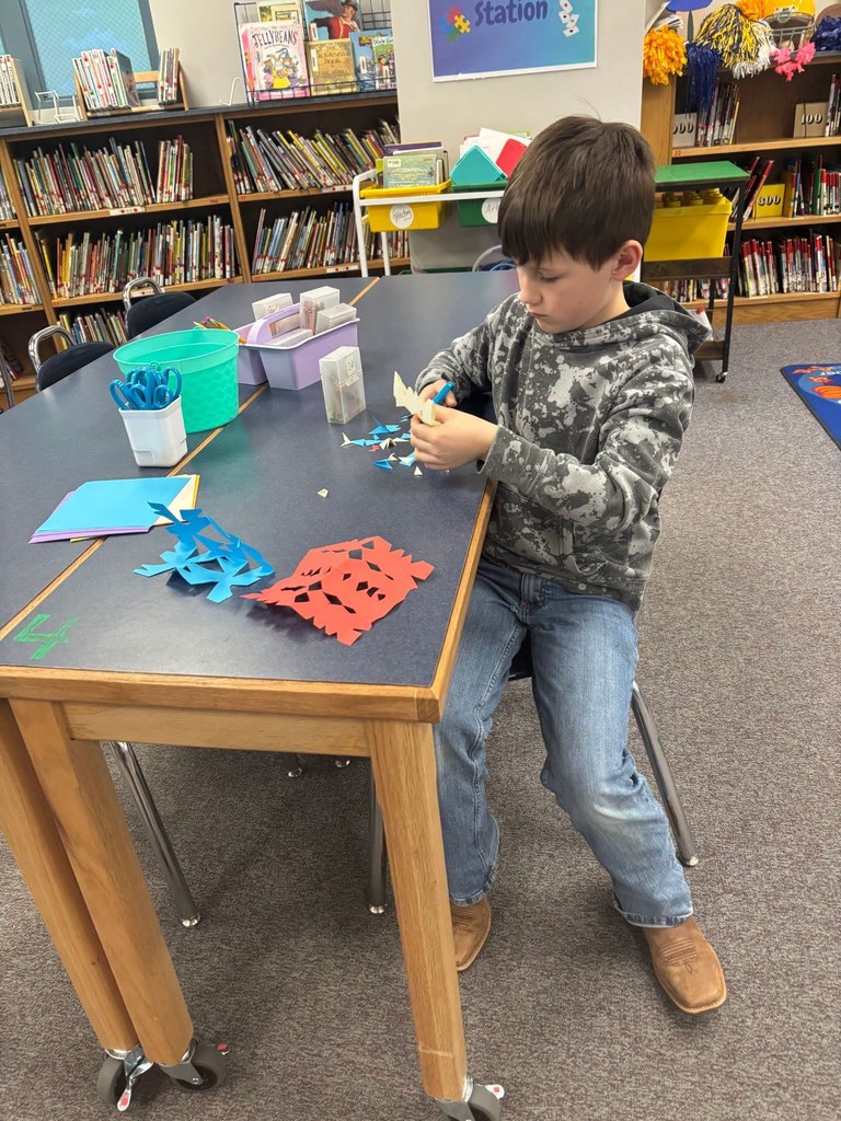 Students using scissors to cut snowflakes