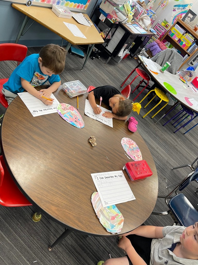 students paint an easter egg with watercolor paints and practicing descriptive writing on space provided under the egg on the paper.