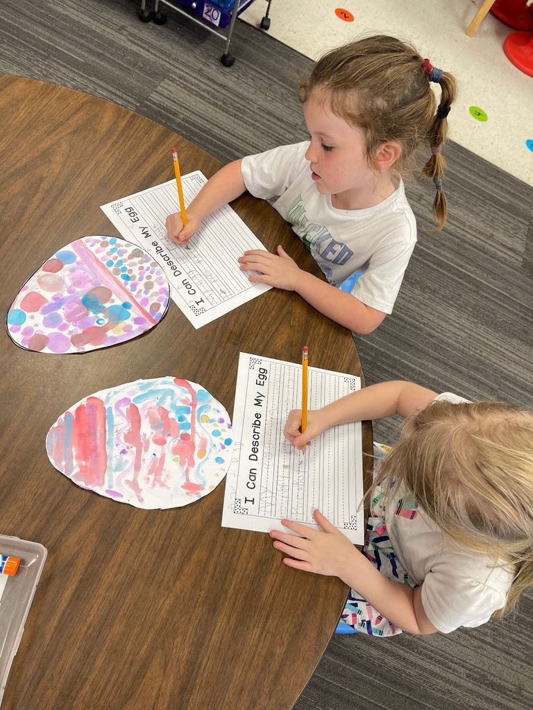 students paint an easter egg with watercolor paints and practicing descriptive writing on space provided under the egg on the paper.