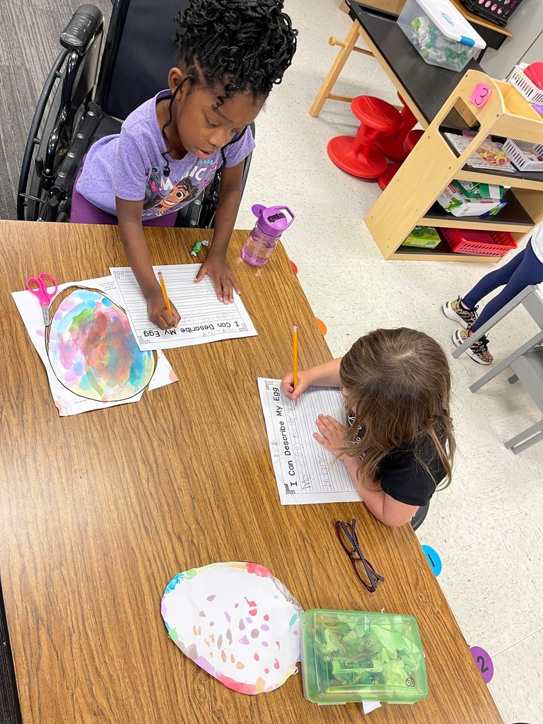 students paint an easter egg with watercolor paints and practicing descriptive writing on space provided under the egg on the paper.