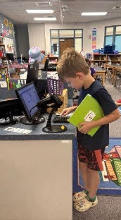 Student typing in his library number on the circulation computer to check out a book