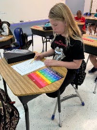 female student working with math fraction tiles