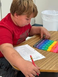 male student working with math fraction tiles