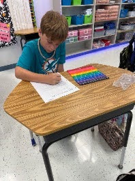 male student working with math fraction tiles