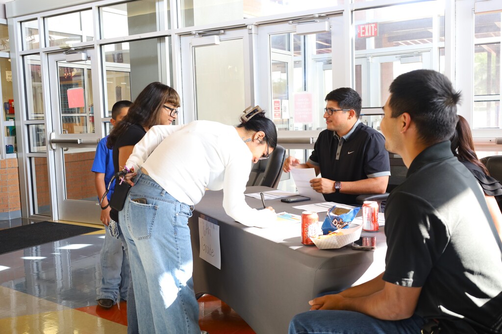 A group of people inside a building. Some are seated while others are standing near a counter.