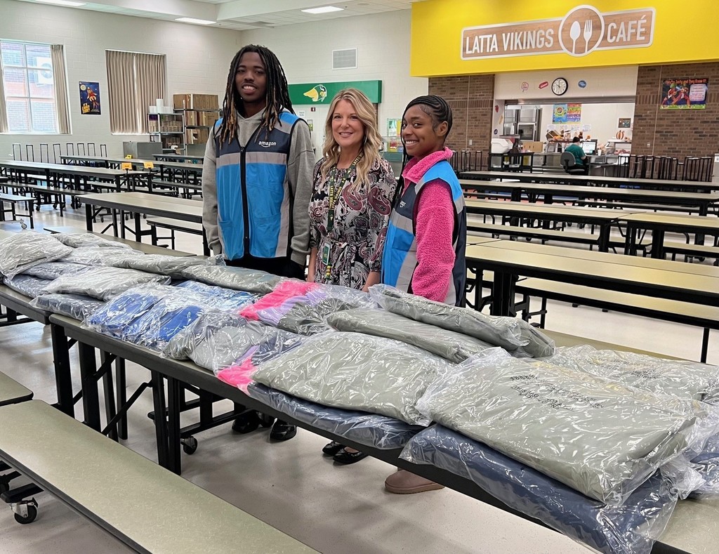 Picture of Darius Wilson, Carla Shelley, and another Amazon delivery driver making a delivery of a donation of coats, hats and socks for students at LES.