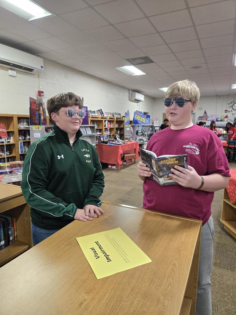 Students attempt to read while wearing visual impairment sunglasses.