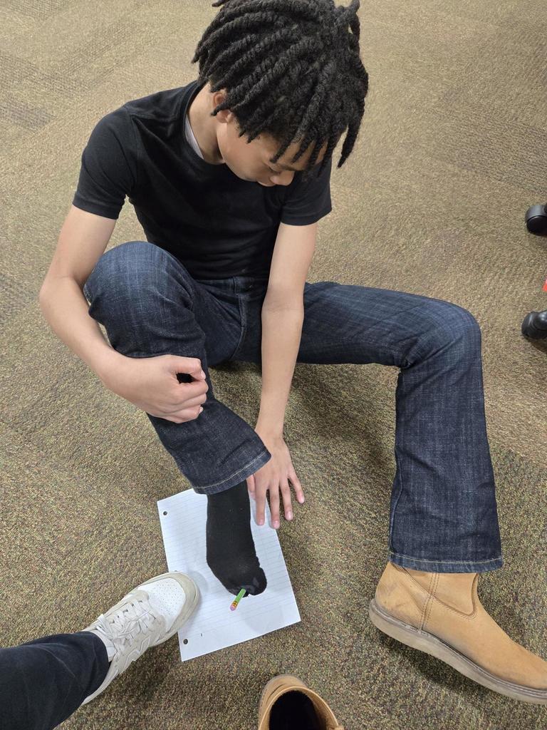 Student attempts to write his name with his foot.