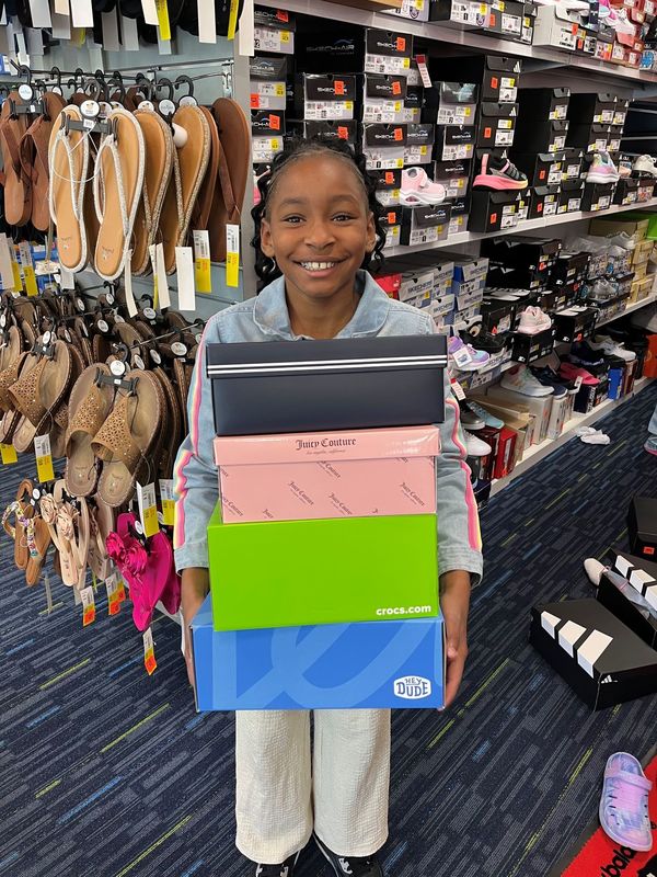 girl holding four pair of shoes