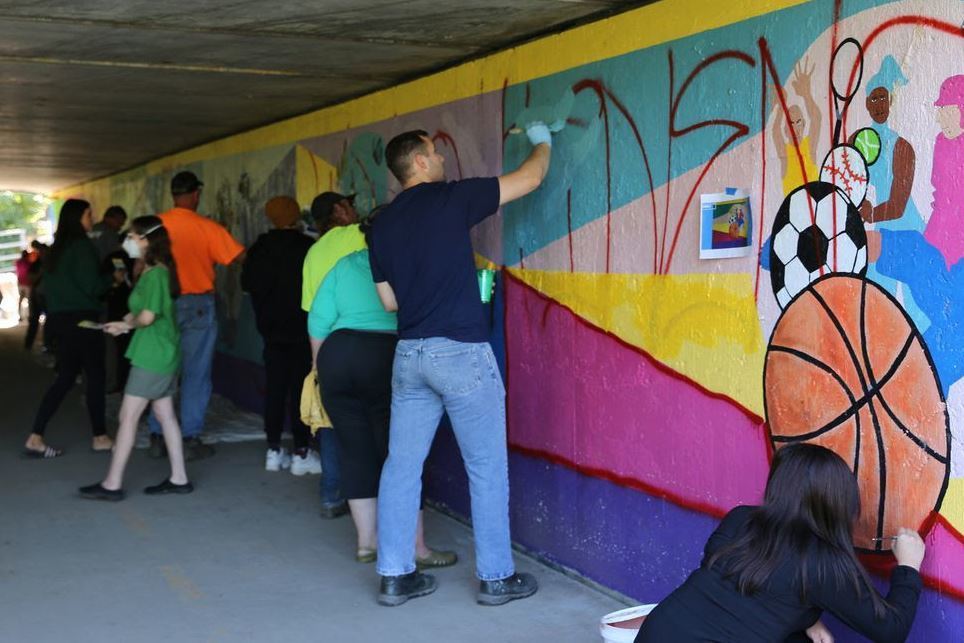 Students and staff working on mural