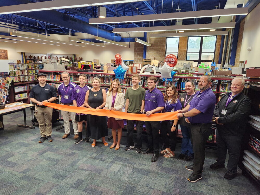 ribbon cutting in RMS library with Dr. Huyett, students and staff smiling for camera