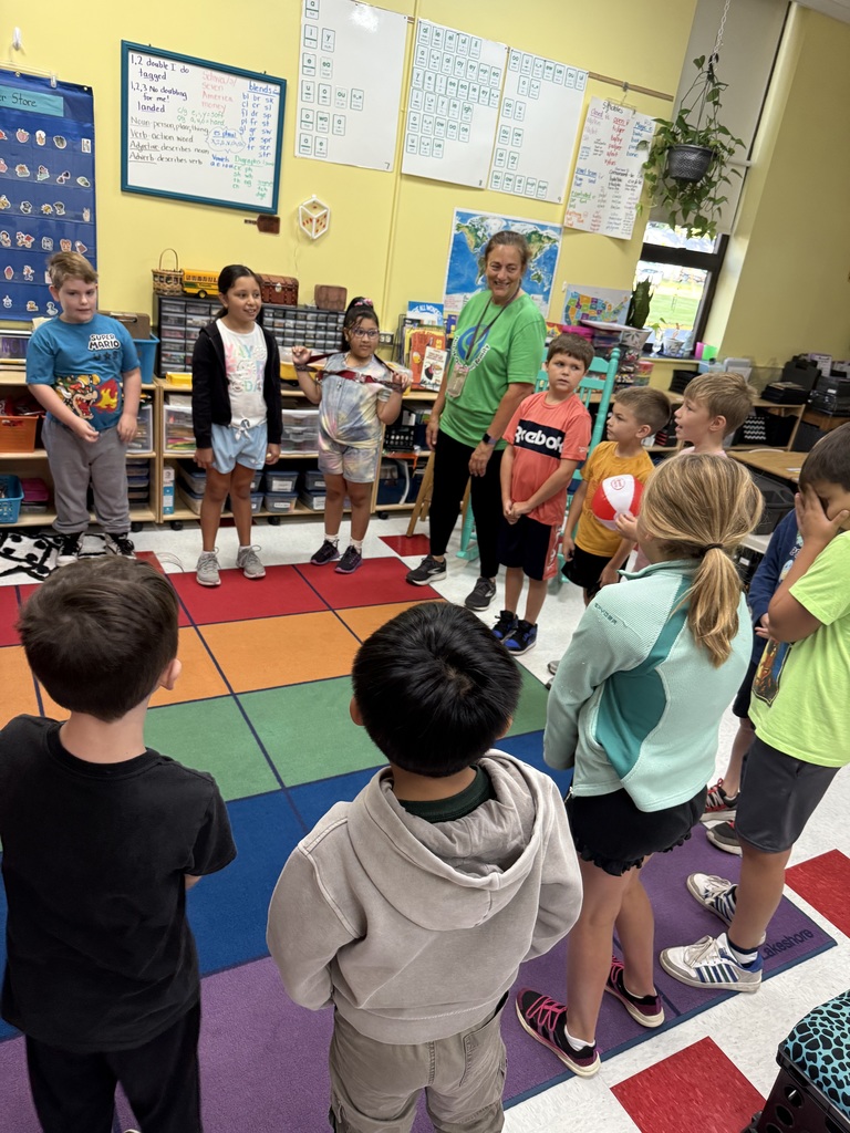 Mrs. Buikema with third graders in a circl at the carpet completing a uniting activity