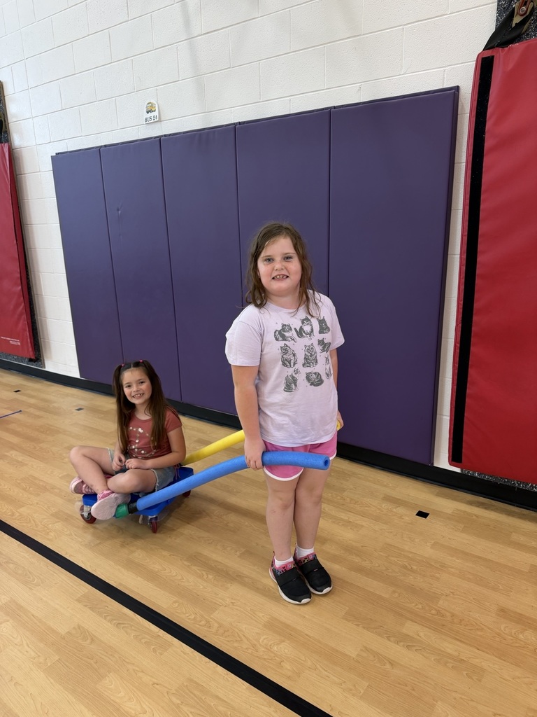 students using scooters to pull each other around the gym