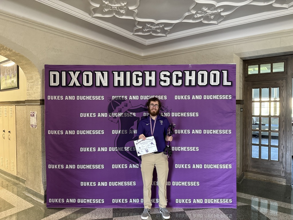 Mr. Sutton holding Spirit Stick Award smiling for camera