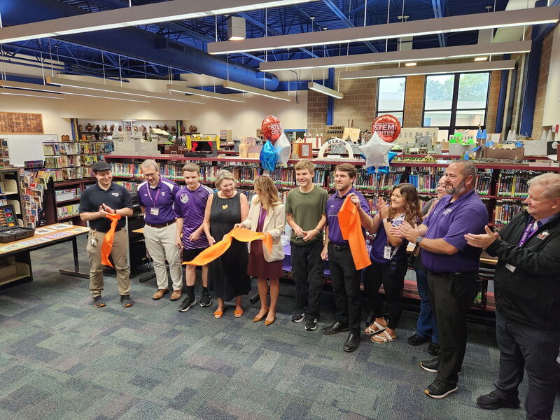 ribbon cutting in RMS library with Dr. Huyett, students and staff smiling for camera