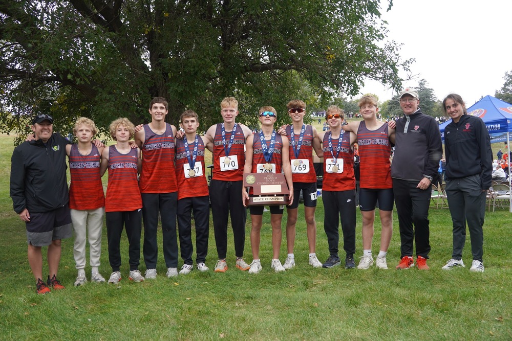 The boys' team is posing with their State Championship plaque.