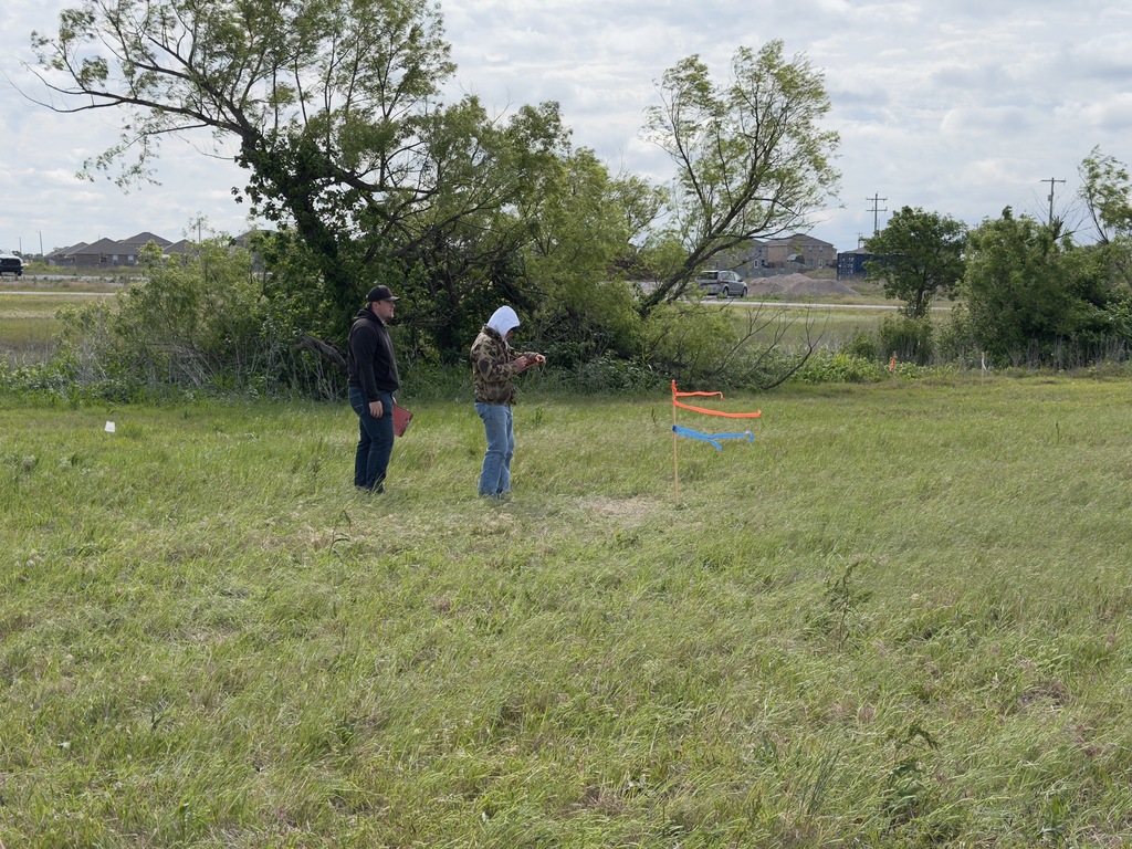 Riley and Jon evaluating slope between two stakes 100 feet apart. 