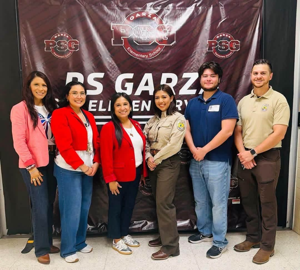 staff posing in front of school sign