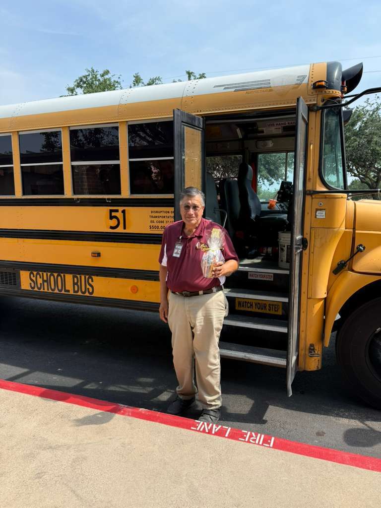 man with maroon shirt in front of yellow bus