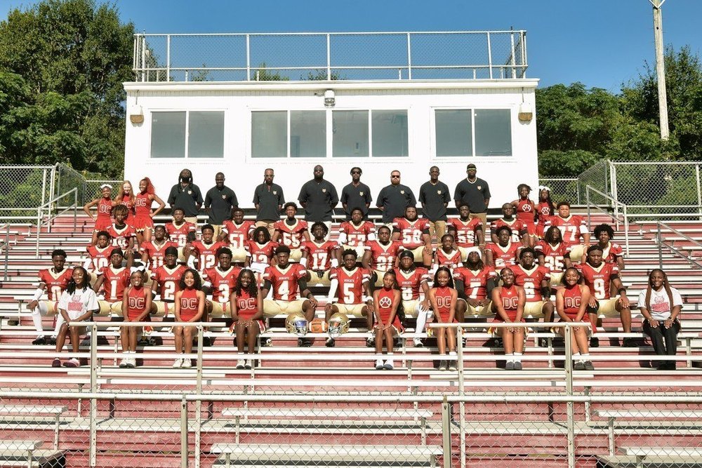 group of football players, coaches, and cheerleaders in the stands
