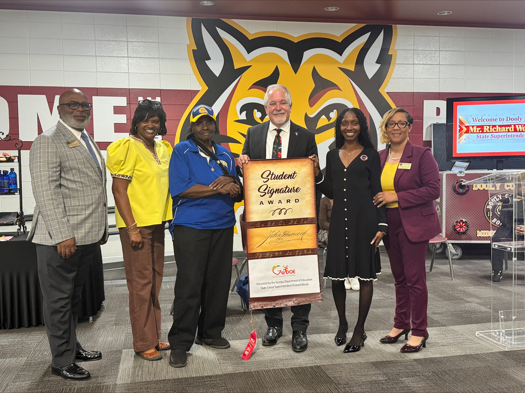 6 people on a stage holding a banner in front of a bobcat logo