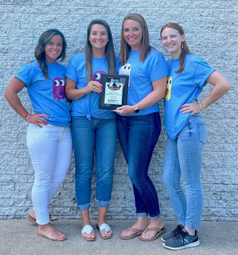 Four teachers holding plaque