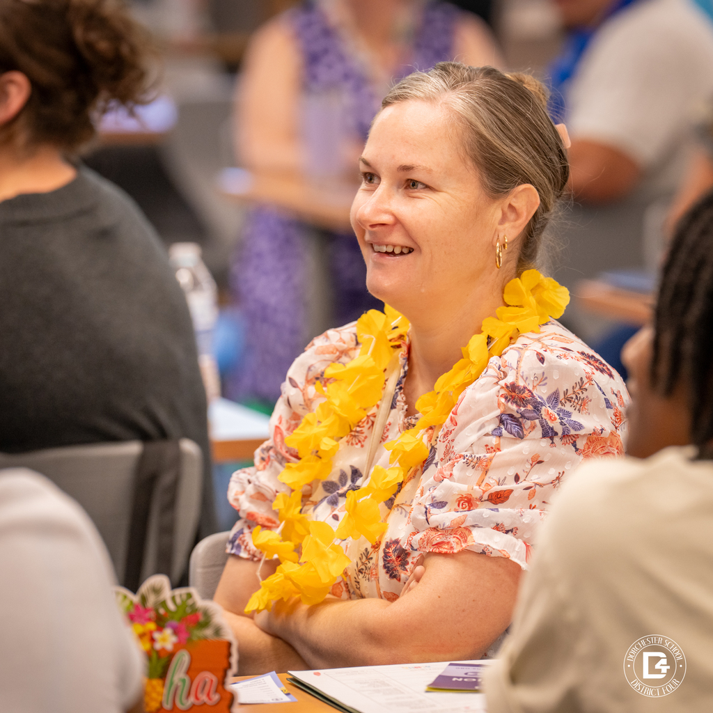 A cheerful new employee wearing a yellow lei listens during the DD4 New Hire Orientation event.
