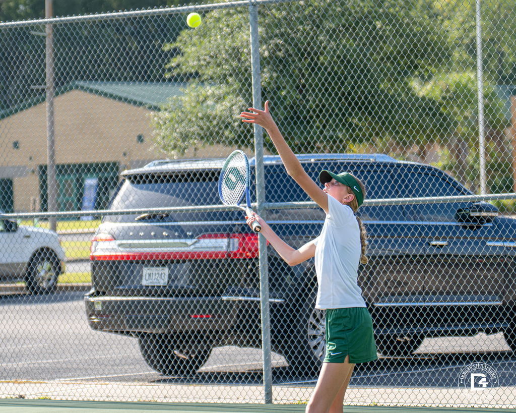A Woodland High School tennis player tosses the ball in the air for a serve during a match.