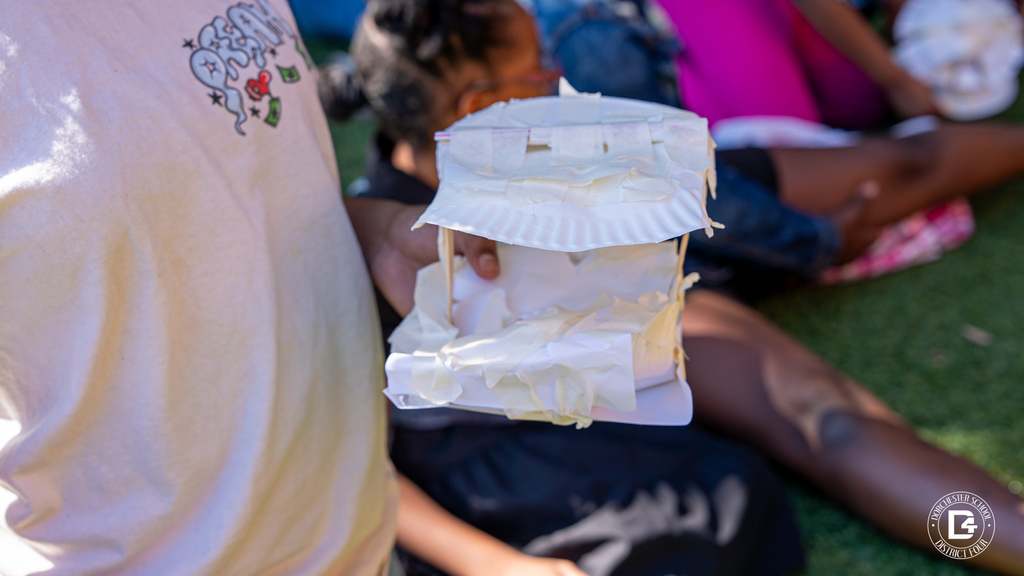 Close-up of a student holding an egg drop project made from stacked paper plates taped together.