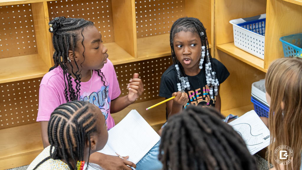 Two students animatedly discuss their answers while comparing perspectives from a story. One student gestures with a pencil while the other listens intently.