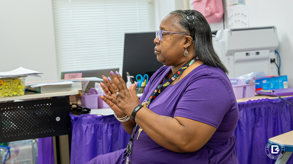 Teacher Patrice Anderson sits at her desk, hands clasped in front of her, watching her students work during a classroom discussion activity at Harleyville Elementary.