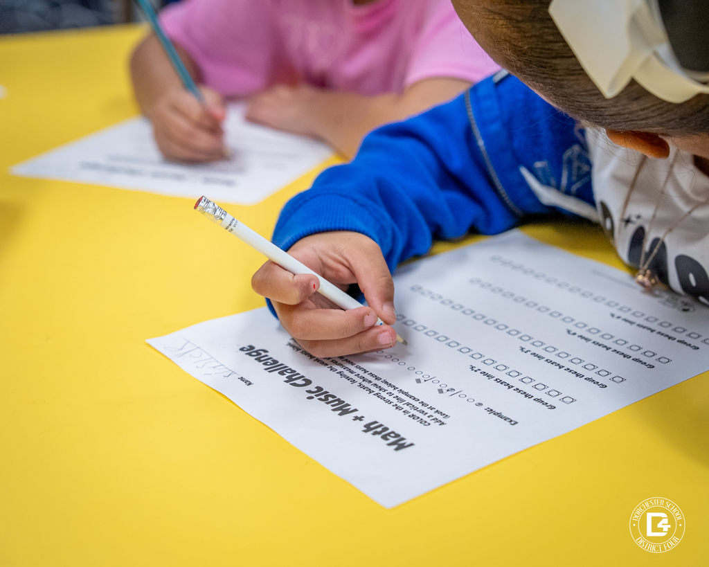 Another close-up view of a student writing on a Math + Music Challenge worksheet, focusing on grouping beats.