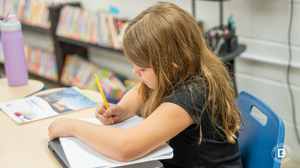 A student writes notes in her notebook while focusing on the science lesson about energy.