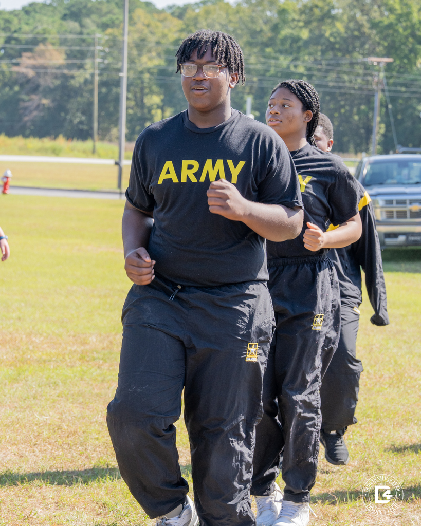 Woodland High JROTC cadets jog in formation across the back lawn during a student-led PT session.