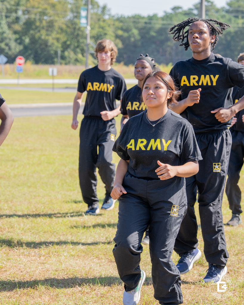 A group of Woodland High JROTC cadets jog together in step, wearing black Army PT uniforms.