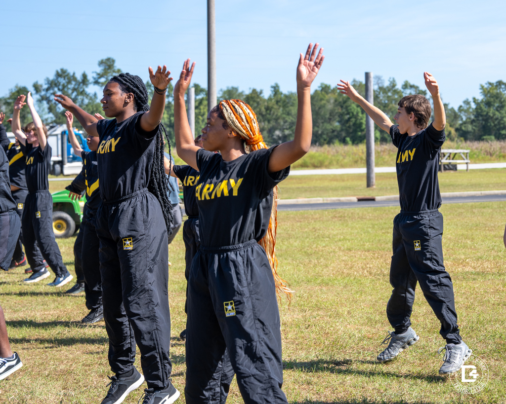 JROTC cadets perform jumping jacks in unison under the morning sun during their student-led workout.