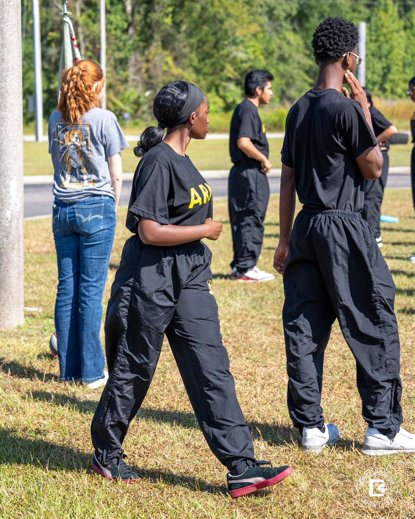 Cadets stand in small groups between exercises, preparing for the next part of their PT session.