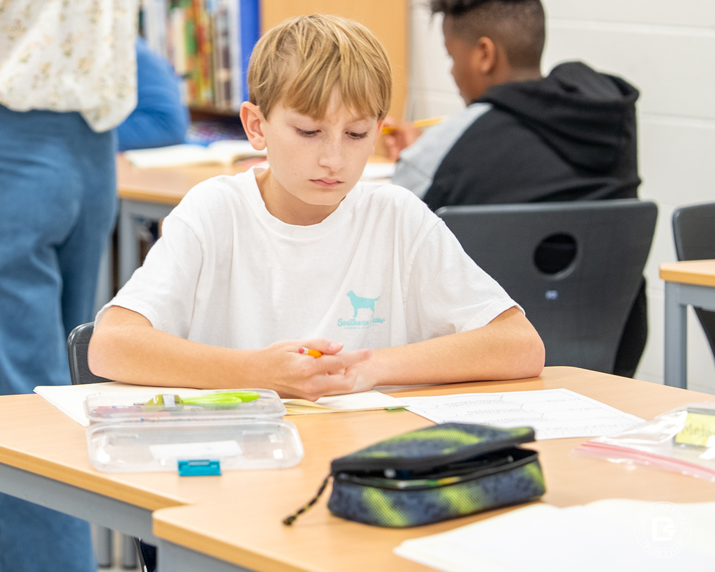A student concentrates on his work, holding a pencil above his notebook during an English lesson.