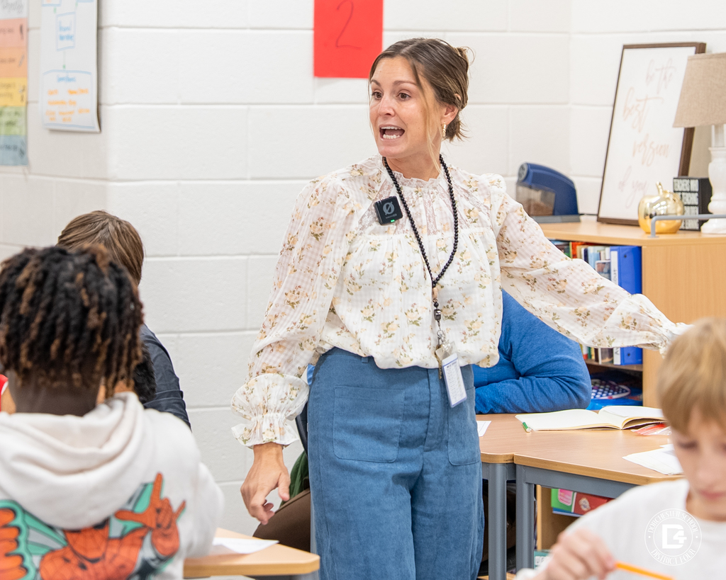 Mrs. Ayer, An English teacher speaks passionately to students, engaging the class in a lively discussion.