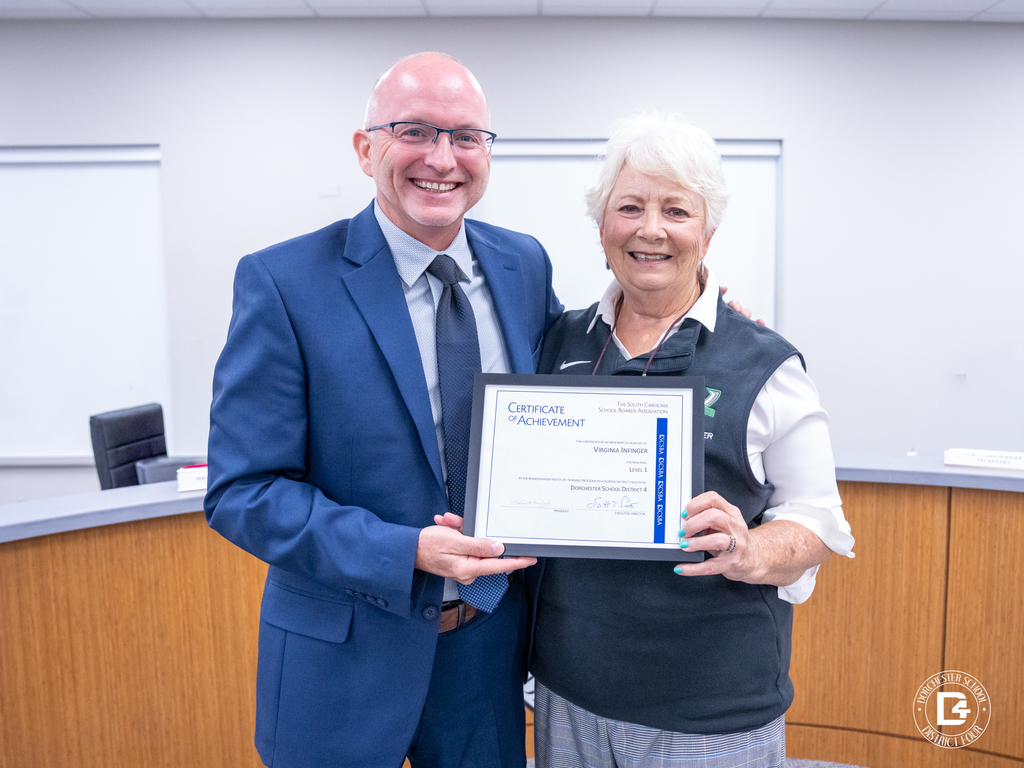 Board member Jenny Infinger stands with Superintendent Jeffrey Beckwith, holding her Certificate of Achievement from the South Carolina School Boards Association recognizing her for achieving Level 1 status.